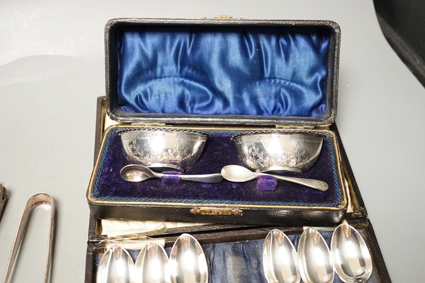 Two pairs of 18th century silver tablespoons including 'berry', a George III silver sifter spoon, pair of sugar tongs and other items including cased plated sets.